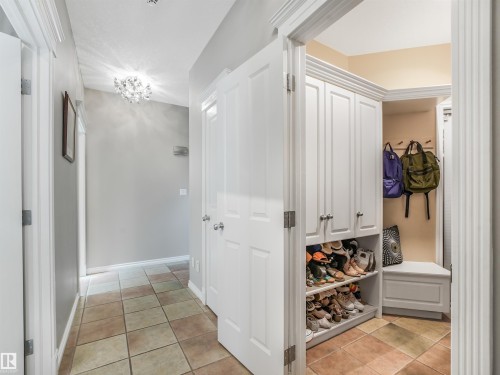 Hallway featuring tile flooring, a decorative ceiling light fixture, white interior doors, and a built-in storage unit with open shelving and an integrated bench - 967 Lamb Crescent Nw, Edmonton, AB - Indoor Photo Showing Other Room