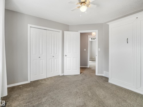 Light grey wall paint with white trim, carpeting, a ceiling fan with integrated lighting, and a built-in wall unit - 967 Lamb Crescent Nw, Edmonton, AB - Indoor