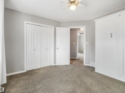 Light grey wall paint with white trim, carpeting, a ceiling fan with integrated lighting, and a built-in wall unit - 