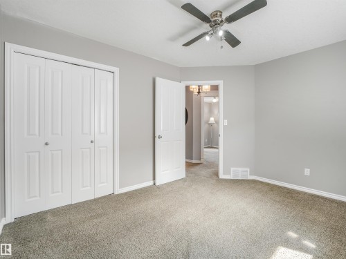 Textured carpet flooring, neutral paint palette, ceiling fan with integrated lighting, white paneled doors, and white trim - 967 Lamb Crescent Nw, Edmonton, AB - Indoor
