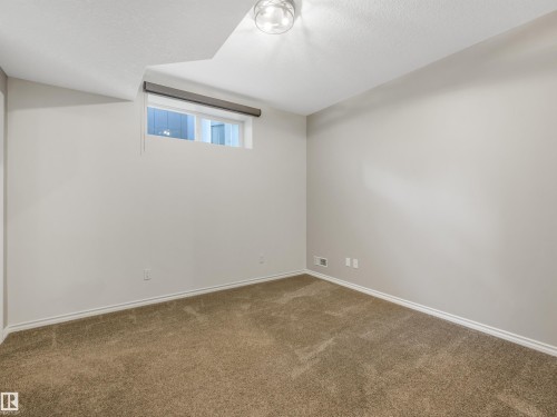 Neutral-toned carpeting, white painted walls, and a single window with a roller shade - 967 Lamb Crescent Nw, Edmonton, AB - Indoor Photo Showing Other Room