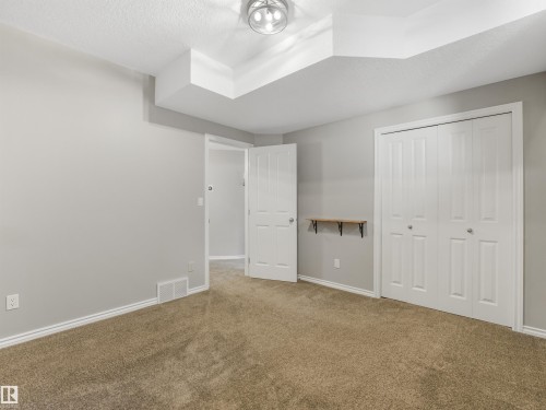 Neutral wall color, carpet flooring, recessed ceiling feature, flush mount light fixture, and bifold closet doors - 967 Lamb Crescent Nw, Edmonton, AB - Indoor Photo Showing Other Room