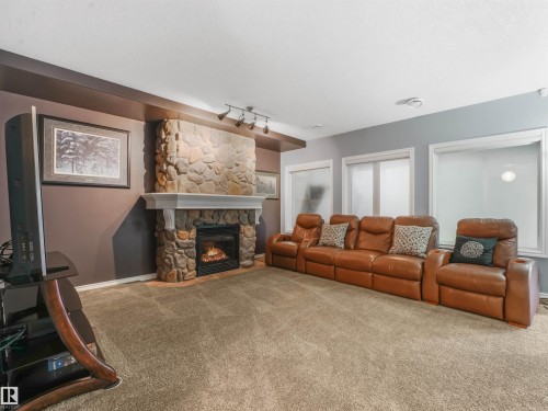 Stone-clad fireplace with mantel, track lighting, and a broad wall with multiple windows - 967 Lamb Crescent Nw, Edmonton, AB - Indoor Photo Showing Living Room With Fireplace