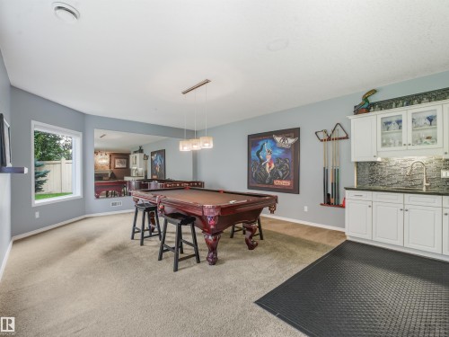 Built-in wet bar with white cabinetry, dark countertop, and mosaic tile backsplash - 967 Lamb Crescent Nw, Edmonton, AB - Indoor Photo Showing Other Room