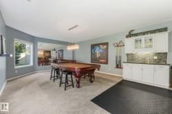 Well-appointed space featuring a built-in wet bar with white cabinetry and dark countertop, recessed lighting, and a large window - 