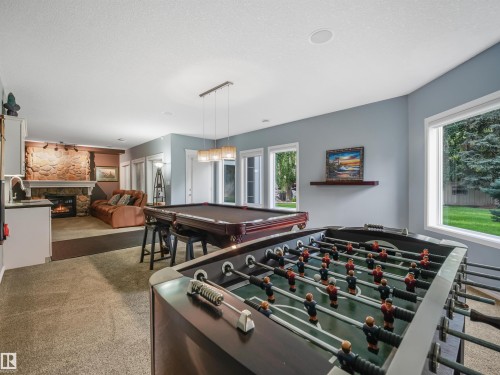 Entertainment room featuring a stone fireplace, recessed lighting, and multiple windows - 967 Lamb Crescent Nw, Edmonton, AB - Indoor
