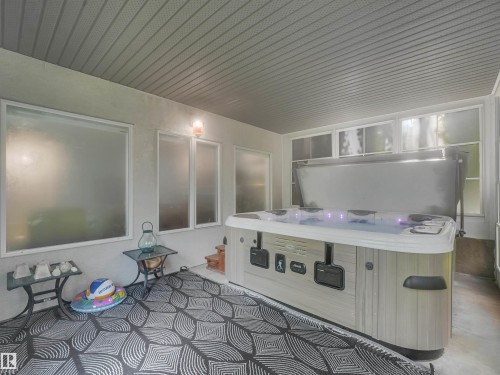 Enclosed hot tub area featuring a textured ceiling, multiple frosted windows, and a built-in hot tub with integrated lighting - 967 Lamb Crescent Nw, Edmonton, AB -  Photo Showing Other Room