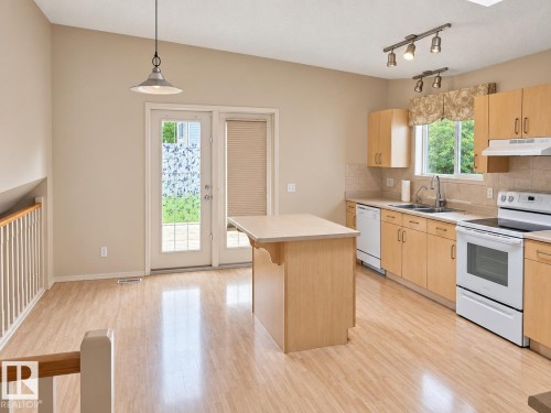 Kitchen featuring wood-finish flooring, light-toned cabinetry, light-toned countertops, and a center island - 507 Wiseman Lane Nw, Edmonton, AB 