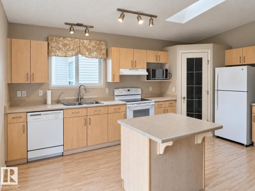 Kitchen featuring wood-finish cabinetry, light-toned countertops, and a central island - 507 Wiseman Lane Nw, Edmonton, AB 