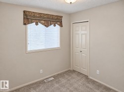 Neutral wall paint, textured ceiling, window with blinds, bi-fold closet door, and carpet flooring - 