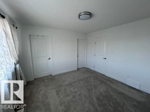 Neutral wall color, wall-to-wall carpeting, contemporary flush mount ceiling light, and interior doors with panel detailing - 20936 16 Avenue Nw, Edmonton, AB - Indoor Photo Showing Other Room