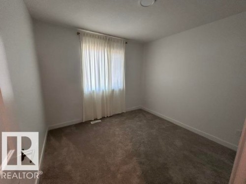Window with vertical blinds, neutral carpeting, and light-colored walls - 20936 16 Avenue Nw, Edmonton, AB - Indoor Photo Showing Other Room