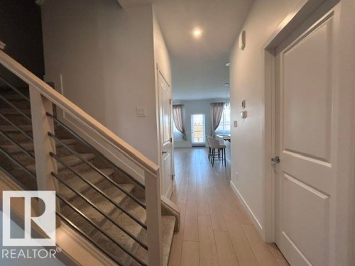 Wood-finish flooring, staircase with carpeted treads, and modern horizontal railing - 20936 16 Avenue Nw, Edmonton, AB - Indoor Photo Showing Other Room
