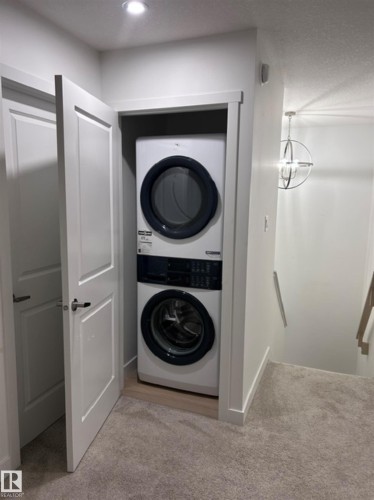 Stackable washer and dryer within a dedicated closet - 20936 16 Avenue Nw, Edmonton, AB - Indoor Photo Showing Laundry Room