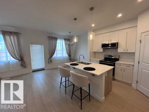 Open concept living area featuring wood-finish flooring - 20936 16 Avenue Nw, Edmonton, AB - Indoor Photo Showing Kitchen With Double Sink