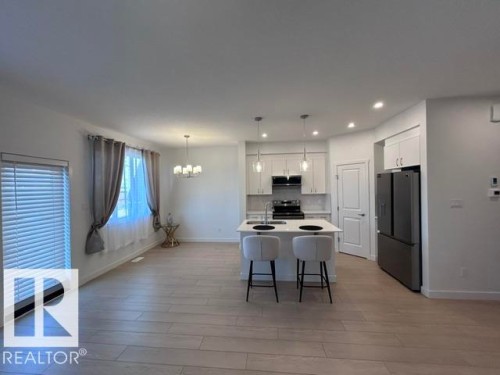 Open concept living space featuring a kitchen island, wood-finish flooring, recessed lighting, and stainless steel appliances - 20936 16 Avenue Nw, Edmonton, AB - Indoor