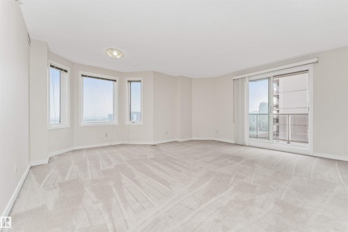 Expansive room with neutral carpeting, multiple windows providing natural light, and a sliding glass door leading to a balcony - #1101 10909 103 Av Nw, Edmonton, AB - Indoor Photo Showing Other Room