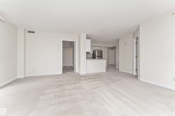 Expansive open-concept living area with light-colored carpeting, recessed lighting, and a white kitchen with stainless steel appliances - 