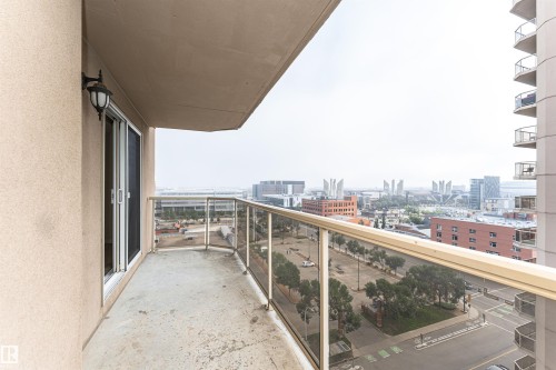 Balcony with a glass and metal railing, offering urban scenery and a wall-mounted exterior light fixture - #1101 10909 103 Av Nw, Edmonton, AB - Outdoor With Balcony With View With Exterior