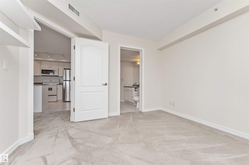 Neutral tone carpeting, white interior doors, and white painted walls - #1101 10909 103 Av Nw, Edmonton, AB - Indoor Photo Showing Other Room