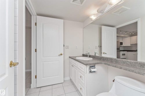 White vanity with a single basin, grey flecked countertop, and large wall-mounted mirror - #1101 10909 103 Av Nw, Edmonton, AB - Indoor Photo Showing Bathroom