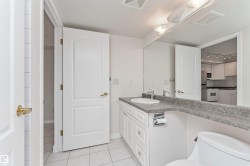 White vanity with a single basin, grey flecked countertop, and large wall-mounted mirror - 