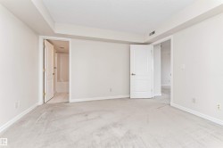 Light-toned wall finishes, neutral carpet flooring, white trim, and a white interior door with brass hardware - 