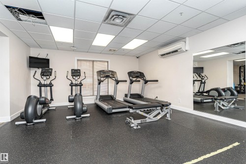 State-of-the-art fitness facility featuring multiple cardio stations including treadmills and elliptical machines, durable composite flooring, mirrored wall paneling for form monitoring, and recessed ceiling lighting throughout the space - #1101 10909 103 Av Nw, Edmonton, AB - Indoor Photo Showing Gym Room