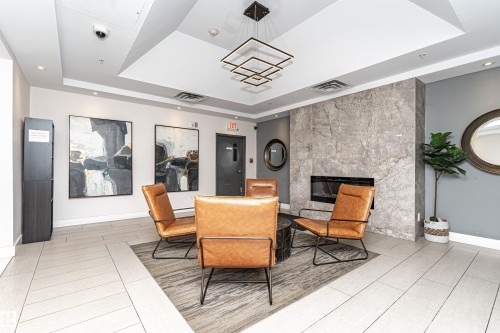 Modern lobby featuring polished light-finish flooring, coffered ceiling with recessed lighting, and a neutral color palette - #1101 10909 103 Av Nw, Edmonton, AB - Indoor With Fireplace