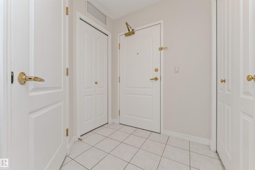 White panel doors, gold-finish hardware, tile flooring, light neutral wall color, and a functional overhead vent - #1101 10909 103 Av Nw, Edmonton, AB - Indoor Photo Showing Other Room