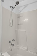 Bathtub with integrated shower surround, chrome fixtures, and handheld showerhead - 