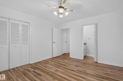 Wood-finish flooring, white walls, louvered bi-fold closet doors, ceiling fan with integrated lighting, and an adjacent room entrance - 