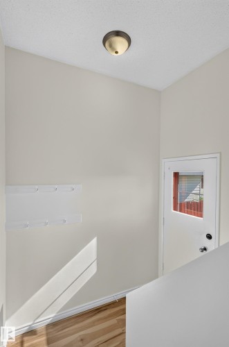 Vaulted ceiling with an attached light fixture, wood-finish flooring, and a white door with an inset window - 13903 87 Street Nw, Edmonton, AB - Indoor Photo Showing Other Room