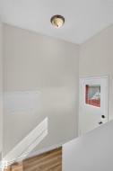Vaulted ceiling with an attached light fixture, wood-finish flooring, and a white door with an inset window - 