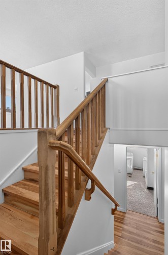 Hardwood staircase featuring a natural wood railing and balusters, with wood-finish flooring extending into the hallway - 13903 87 Street Nw, Edmonton, AB - Indoor Photo Showing Other Room