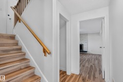 Wood-finish flooring throughout, featuring a natural wood staircase with matching handrail - 