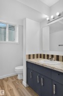 Vanity with a single basin, wood-finish flooring, and a window - 
