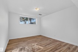 Wood-finish flooring, white walls, and a window providing natural light - 