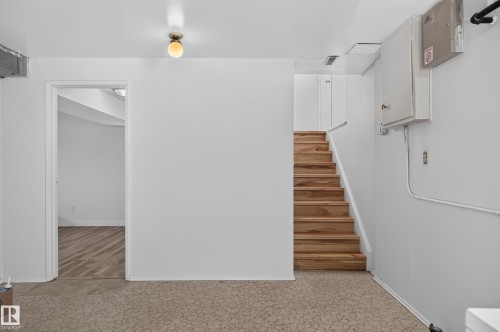 Wood stairs with painted handrail, overhead light fixture, light-colored walls, and wood-finish flooring in an adjacent room - 13903 87 Street Nw, Edmonton, AB - Indoor Photo Showing Other Room