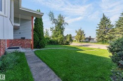 Concrete walkway leading to a front entry with a red brick facade and light blue siding - 