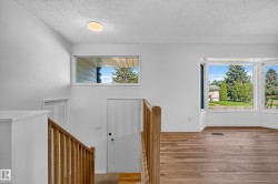 Hardwood-finish flooring, white walls, and a multi-pane bay window - 