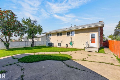 Rear exterior with a concrete patio, brick chimney, and a chain-link fence - 13903 87 Street Nw, Edmonton, AB - Outdoor