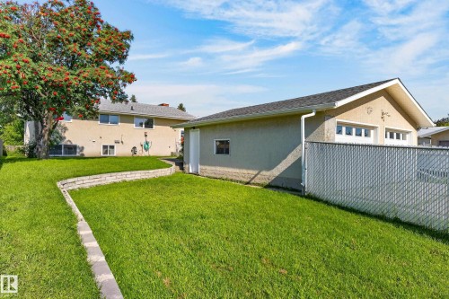 Expansive backyard featuring a manicured lawn, established tree, and retaining wall - 13903 87 Street Nw, Edmonton, AB - Outdoor
