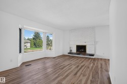 Expansive bay window, wood-finish flooring, white brick fireplace, dark hearth, and light-toned wall finishes - 