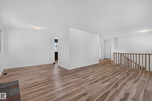 Spacious room with wood-finish flooring, light-colored walls, and a wood railing - 13903 87 Street Nw, Edmonton, AB - Indoor Photo Showing Other Room