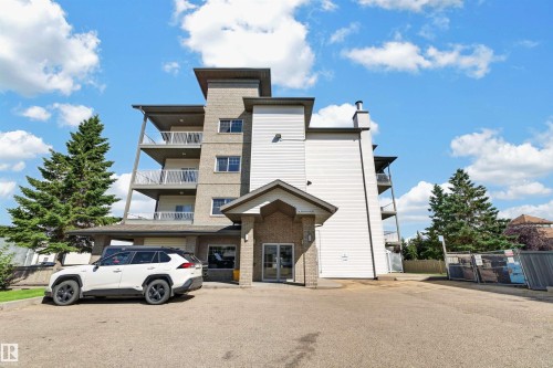 Multi-story exterior featuring a prominent entrance canopy, multiple balconies with metal railings, and a combination of brick and siding finishes - #107 16715 100 Av Nw, Edmonton, AB 