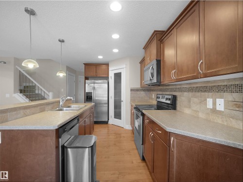 Kitchen featuring wood-finish cabinetry, stainless steel appliances, and durable countertops - 17127 126 Street Nw, Edmonton, AB - Indoor Photo Showing Kitchen With Double Sink