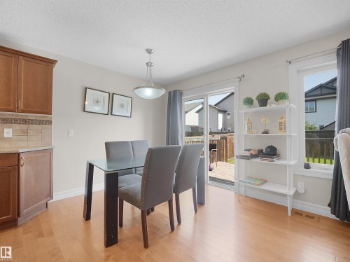 Wood-finish flooring, built-in cabinetry, tiled backsplash, ceiling-mounted light fixture, and sliding glass door to outdoor decking - 17127 126 Street Nw, Edmonton, AB - Indoor Photo Showing Dining Room
