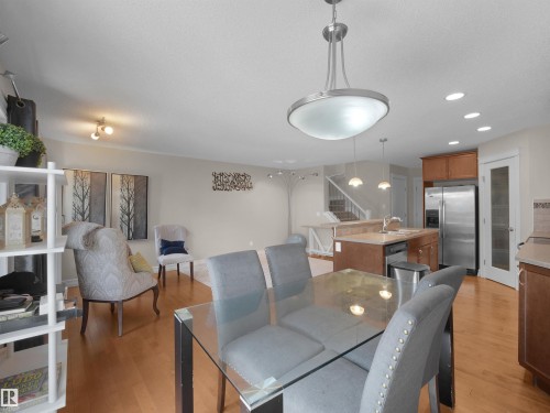 Open-concept living area with wood-finish flooring, kitchen island, and stainless steel appliances - 17127 126 Street Nw, Edmonton, AB - Indoor
