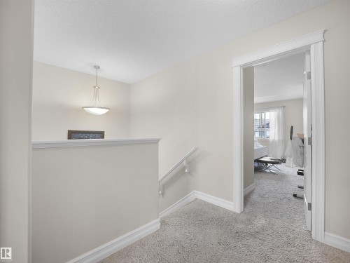 Carpeted landing with white trim, a decorative pendant light, and a white handrail - 17127 126 Street Nw, Edmonton, AB - Indoor Photo Showing Other Room